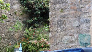 A stone wall with a hot tub and a stone table with a bottle and glasses. - Nancherrow Studio (Penzance)