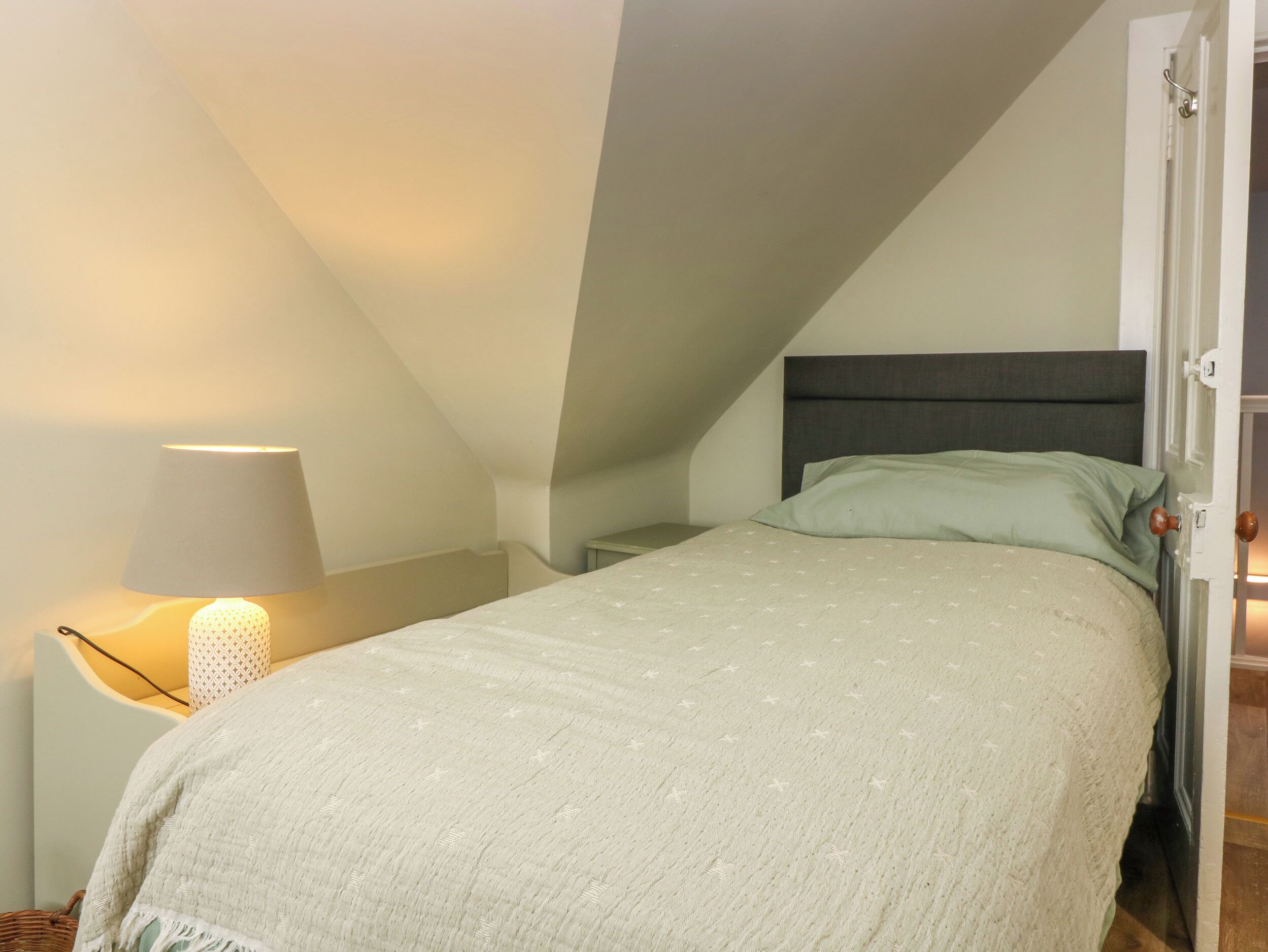 Une chambre à coucher avec un lit, une table de chevet, une lampe et une porte.