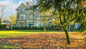 A large stone building with multiple windows and a well-maintained lawn. - Castleton Suite (Buxton)