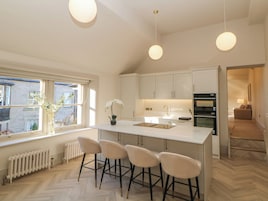 Una cucina moderna con isola centrale, sgabelli da bar, una finestra vista e illuminazione a sospensione.