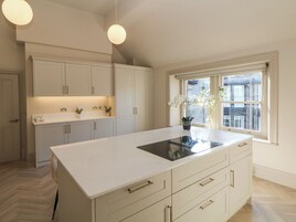 A modern kitchen with white cabinetry, a large island with a sink, and a window with a view of buildings.
