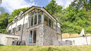 A modern house with a stone facade, large windows, and a covered patio area. - Bryn Golau (Llangollen)