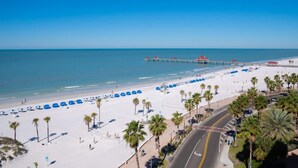 Una playa con un muelle, sombrillas y palmeras.
