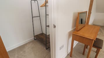 A room with a wooden table, a mirror, a coat rack, and a door.