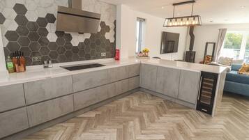 Una cocina moderna con piso de madera en espiga, horno empotrado y una isla grande con pileta.