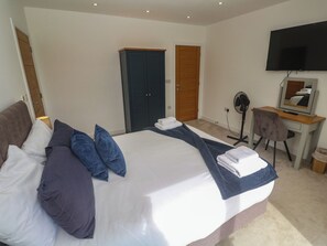 Une chambre d’hôtel avec un grand lit, un bureau avec une chaise, une télévision et une armoire.