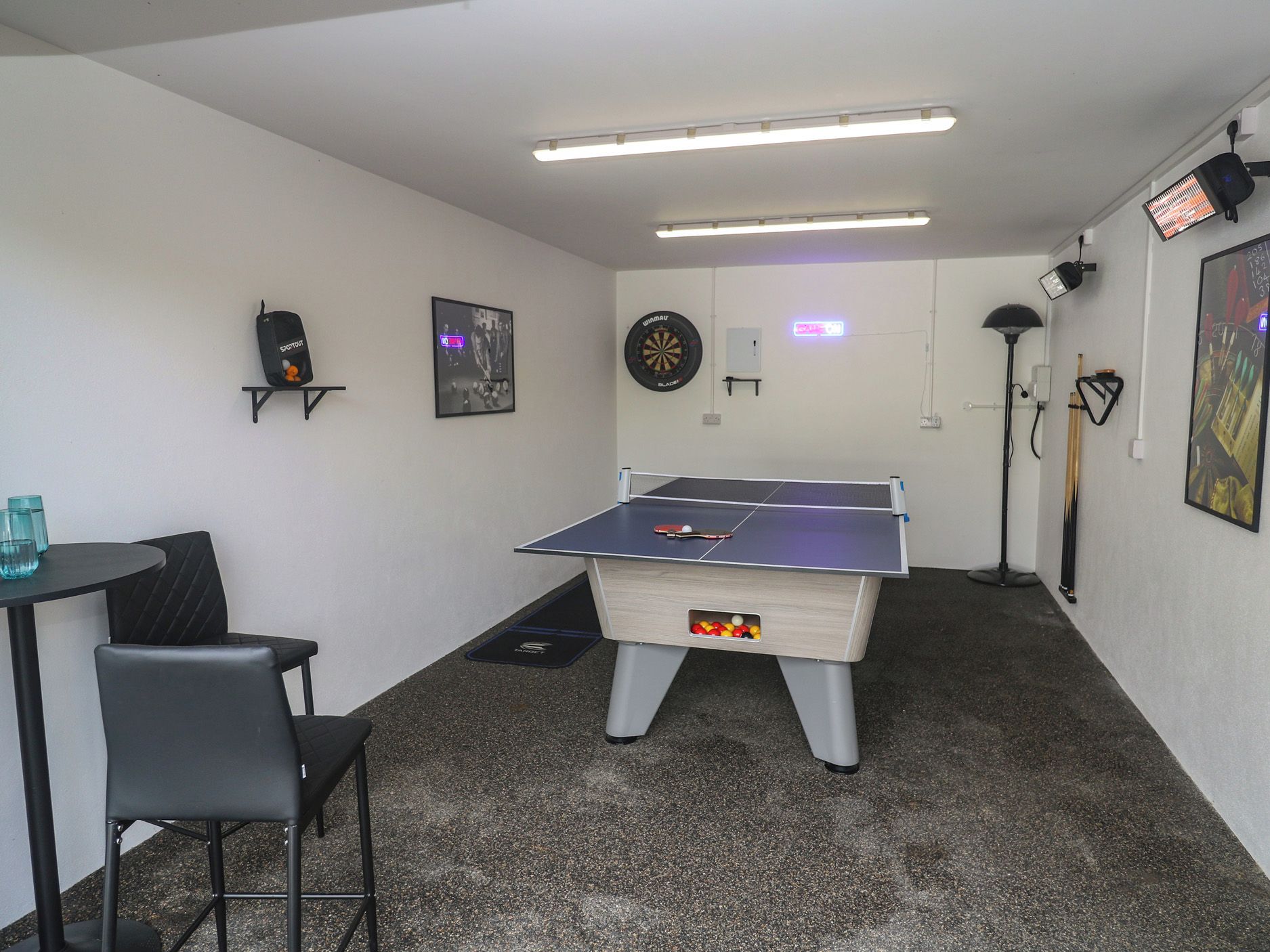 Une pièce équipée d’une table de ping-pong, d’un jeu de fléchettes et d’un billard.