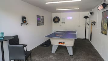 Une pièce équipée d’une table de ping-pong, d’un jeu de fléchettes et d’un billard.