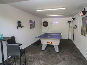 Una stanza con tavolo da ping pong, bersaglio di freccette e tavolo da biliardo.