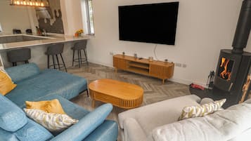 Una sala de estar moderna con un sofá, una mesa de centro, un televisor y una estufa de leña.