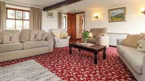 A living room with a red patterned carpet, two sofas, a wooden coffee table, and a painting on the wall. - Addyfield Farmhouse (Windermere)