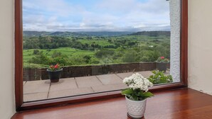 A view from a window overlooking a green landscape with fields and distant hills. - Addyfield Farmhouse (Windermere)