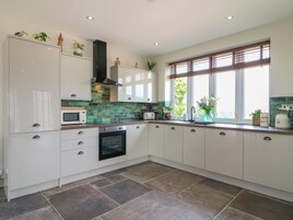 A modern kitchen with white cabinets, a microwave, an oven, and a window with blinds.