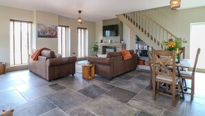 A spacious living room with a fireplace, two sofas, a coffee table, and a dining area with chairs and a table. - Cherry Tree Cottage (Chesterfield)