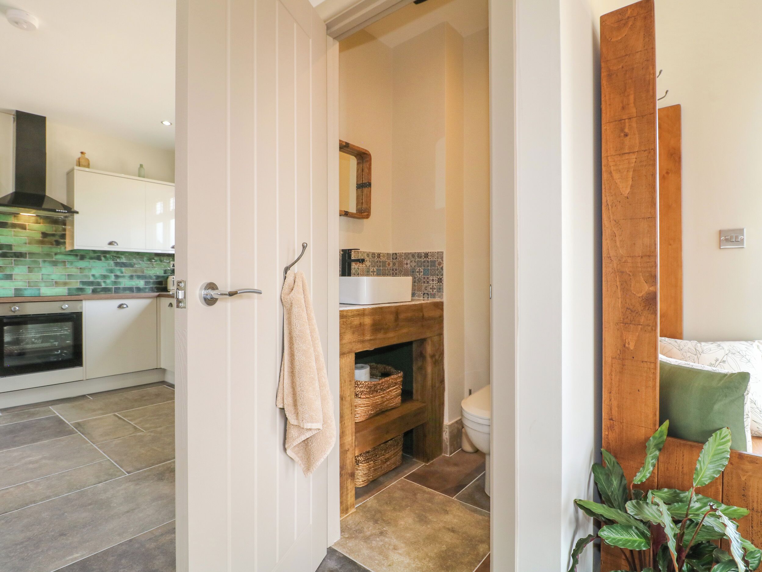 Una cocina con salpicadero de azulejos, repisa de madera y toalla colgante.