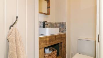 Ein Badezimmer mit einem Holzkosmetikschrank, einem Waschbecken, einer Toilette und einem Handtuch, das an einem Haken hängt.