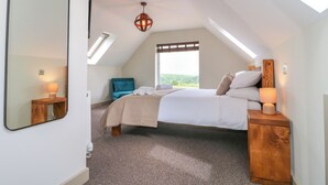 A bedroom with a bed, a chair, a bedside table, a mirror, and a skylight. - Cherry Tree Cottage (Chesterfield)