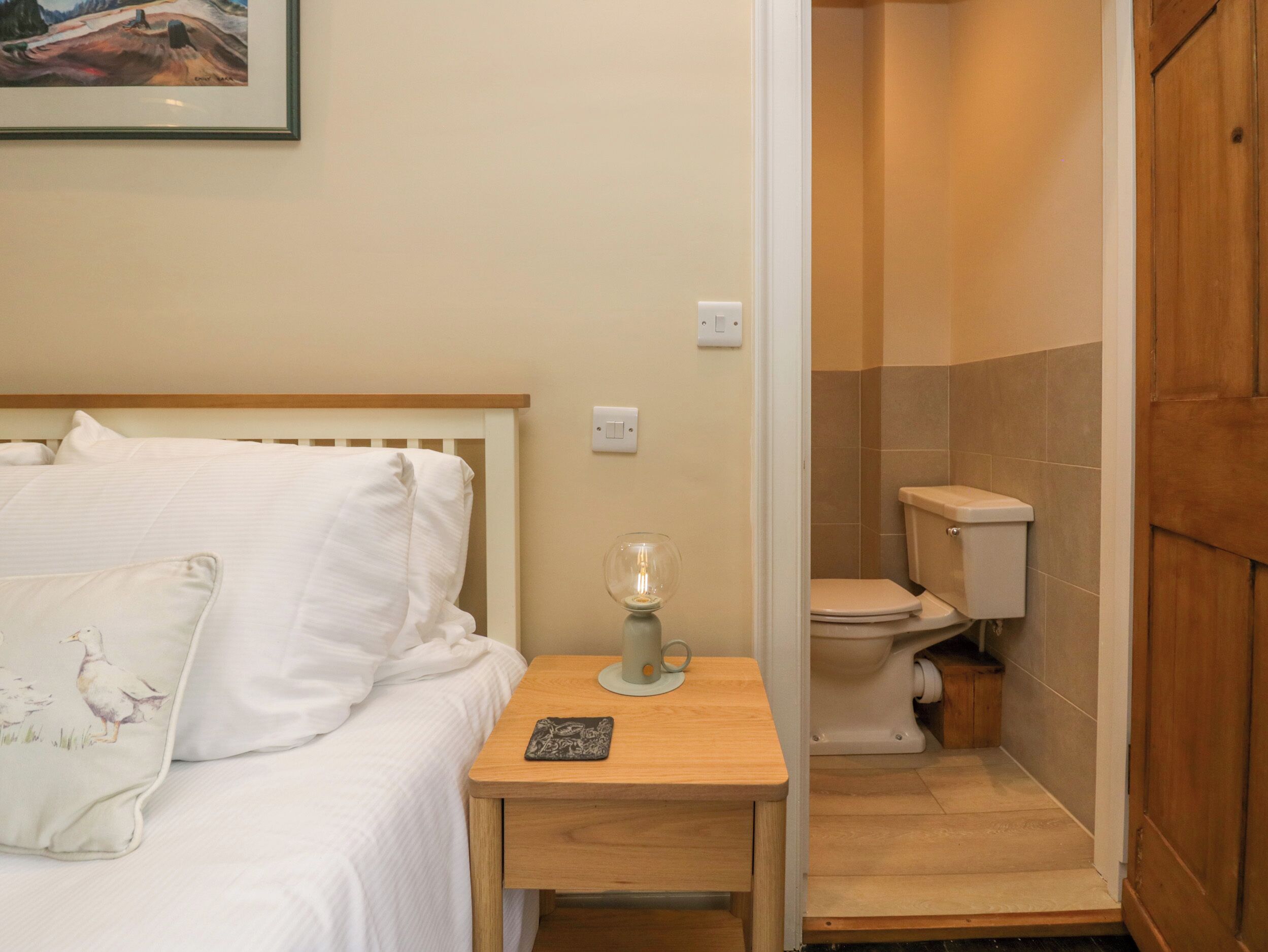 A bedroom with a bed, bedside table, and a nightstand with a lamp.