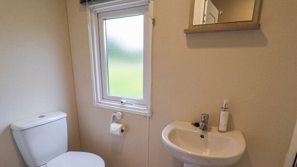 A small bathroom with a toilet, a sink, and a window. - The Hoot (Stowmarket)