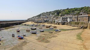Une ville côtière avec des bateaux sur une plage de sable et des bâtiments sur une colline.
