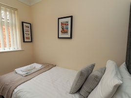 Un dormitorio con cama, una ventana con persianas y dos cuadros en la pared.