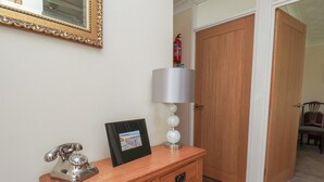 A wooden desk with a telephone, a framed picture, and a lamp with a decorative base.