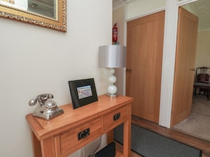 A wooden desk with a telephone, a framed picture, and a lamp with a decorative base. - Sea Roke (Filey)