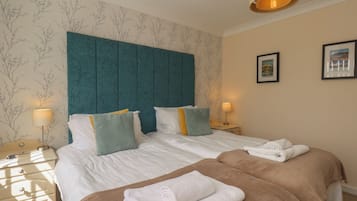 Habitación de hotel con una cama grande, dos mesitas de noche, un cabecero y dos cuadros enmarcados en la pared.