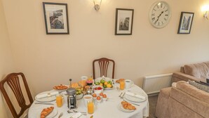 A dining area with a table set for breakfast, including croissants, fruits, and beverages.
