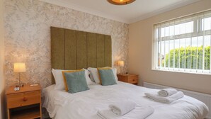 A hotel room with a large bed, two bedside tables, a window with a view, and a ceiling light fixture.