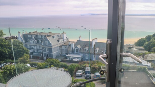 A view from a balcony overlooking a coastal town with buildings and a beach. - Amelia's Point (St Ives)