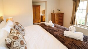 Una camera d'albergo con un letto grande, un armadio, una cassettiera e una finestra con tende.