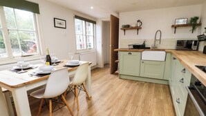 Una cucina moderna con zona pranzo, pavimento in legno e vista sull'esterno.