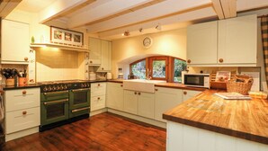 Eine Küche mit Holzboden, weißen Schränken, einem grünen Herd und einer Holz Arbeitsplatte.