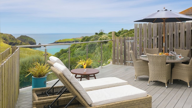 A deck with wicker furniture, a table with chairs, and a potted plant. - Daphne (Helston)