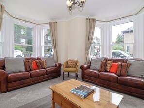 A living room with two brown leather sofas, a wooden coffee table, and a yellow armchair. - Melbreak House 2 (Keswick)