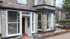 A stone building with a glass door entrance, a sign reading "MEIR BREAK HOUSE," and a small porch area. - Melbreak House 2 (Keswick)