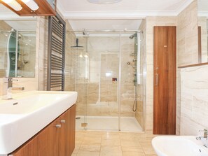 A modern bathroom with a glass-enclosed shower, a wooden vanity, and a separate sink. - The Warren M45 (Pwllheli)