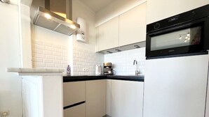 Et moderne køkken med hvide skabe, en sort bordplade og en indbygget ovn.