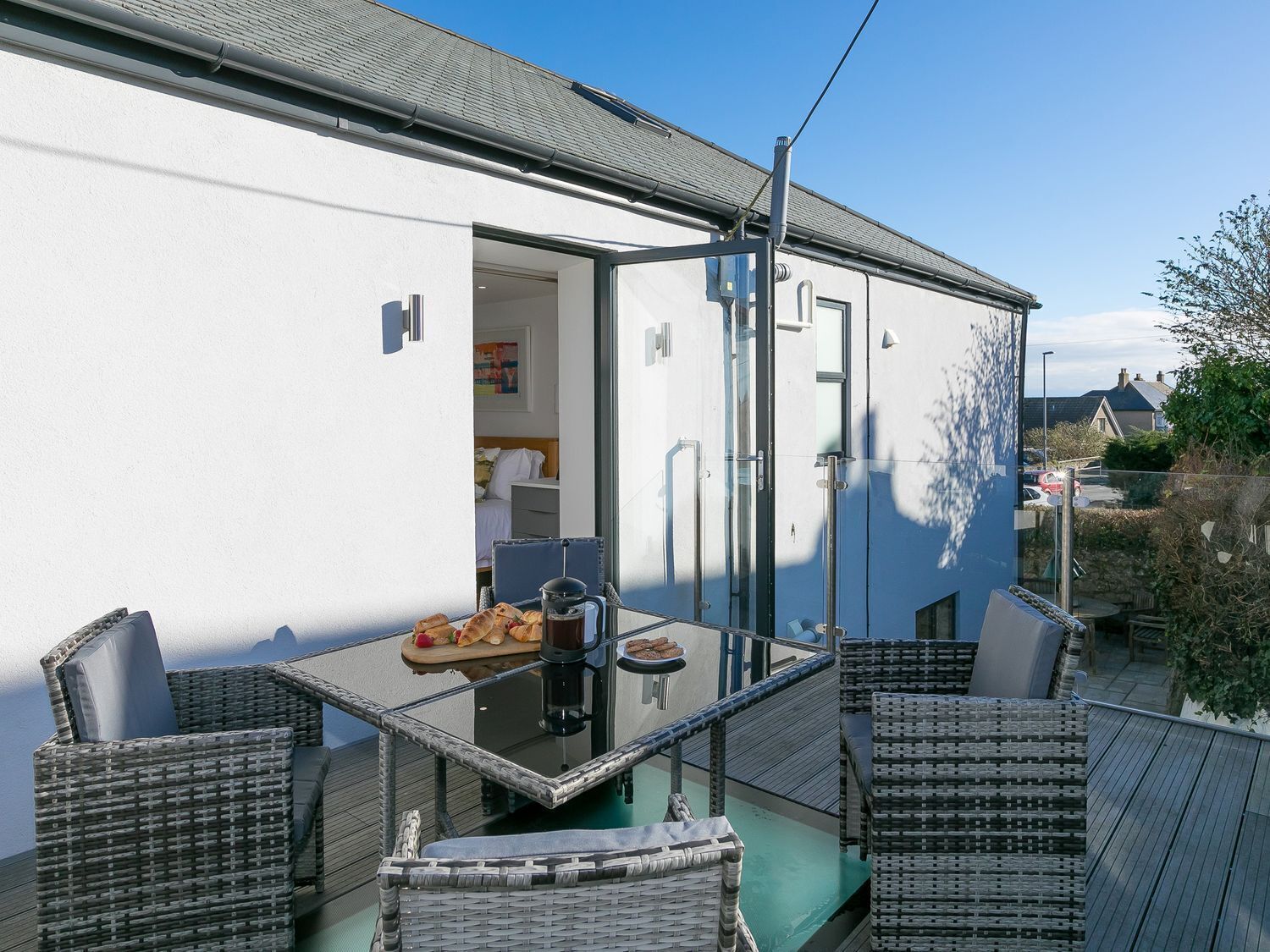 A balcony with wicker furniture, a table with food, and a glass door leading to a room.