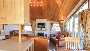 A cozy living room with wooden furniture, a fireplace, and a TV mounted on the wall. - Kellet Lodge (Carnforth)