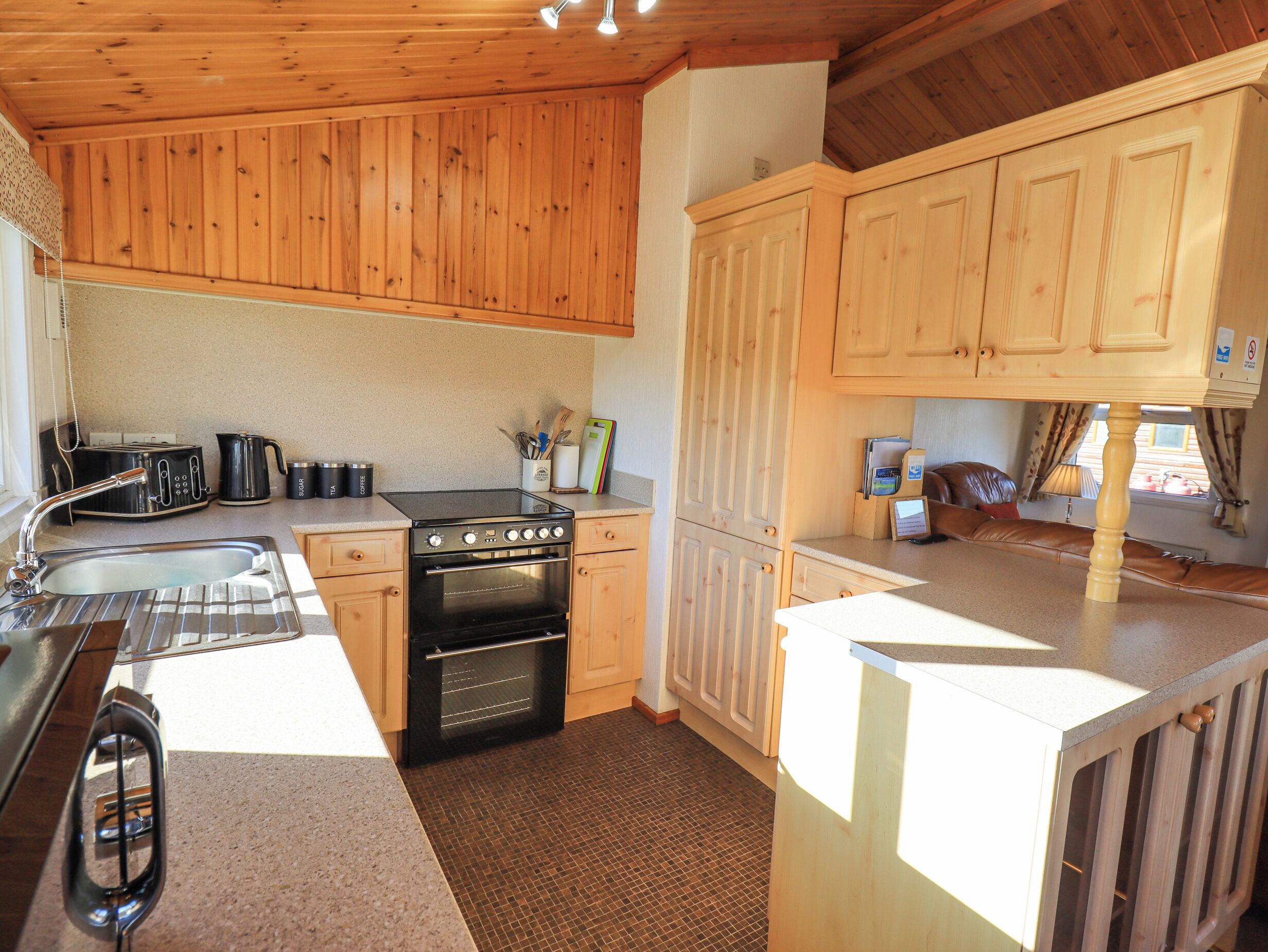A compact kitchen with wooden cabinets, a stove, and a sink.