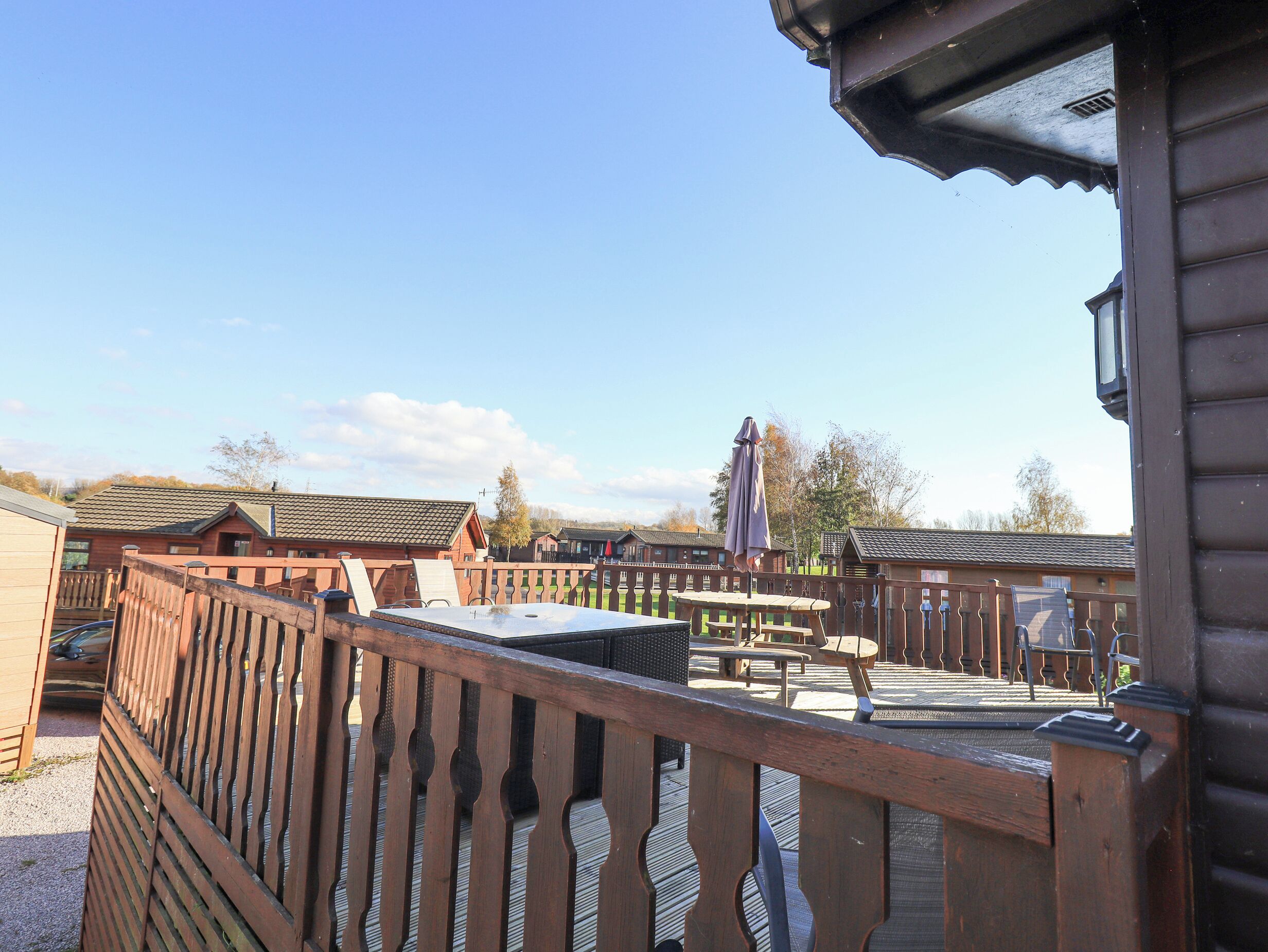 A wooden deck with a railing, a table, and chairs.