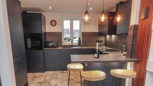 Una cocina moderna con armarios oscuros, una encimera de madera y una zona de bar con taburetes.
