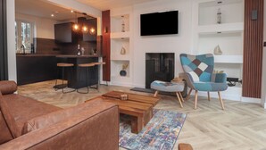 Una sala de estar moderna con un sofá, una mesa de centro, una alfombra estampada, un televisor y una chimenea.