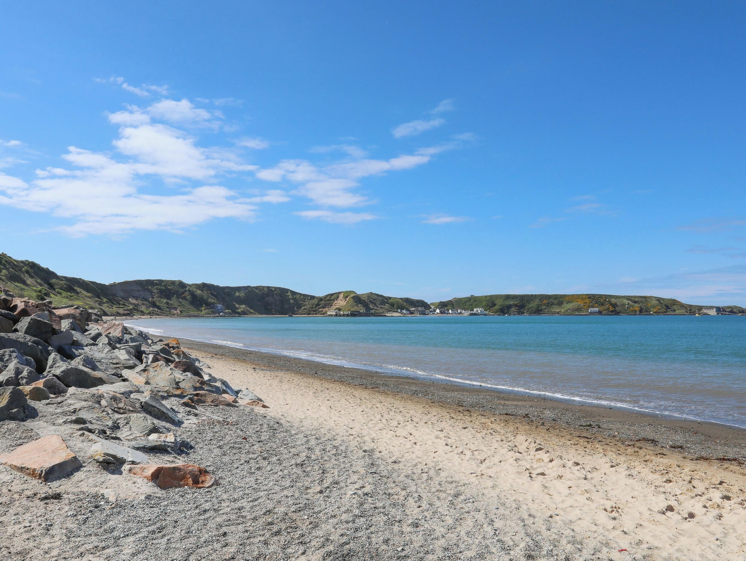 A beach with rocky terrain and a clear blue sky.