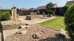 A garden with a stone wall, a wooden fence, and a lawn. - 36 Chatsworth Close (Bridlington)