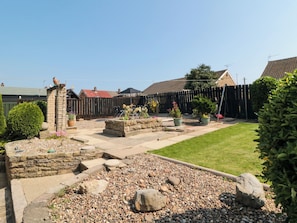 A garden with a stone wall, a wooden fence, and a lawn. - 36 Chatsworth Close (Bridlington)