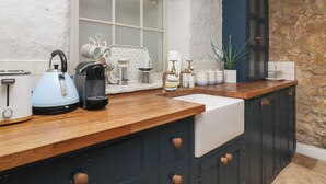 Una cocina con encimera de madera, hervidor, tostadora y pileta.