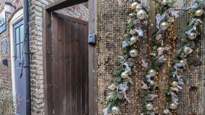 Una puerta de madera con una celosía metálica y decoraciones festivas, como piñas y luces.